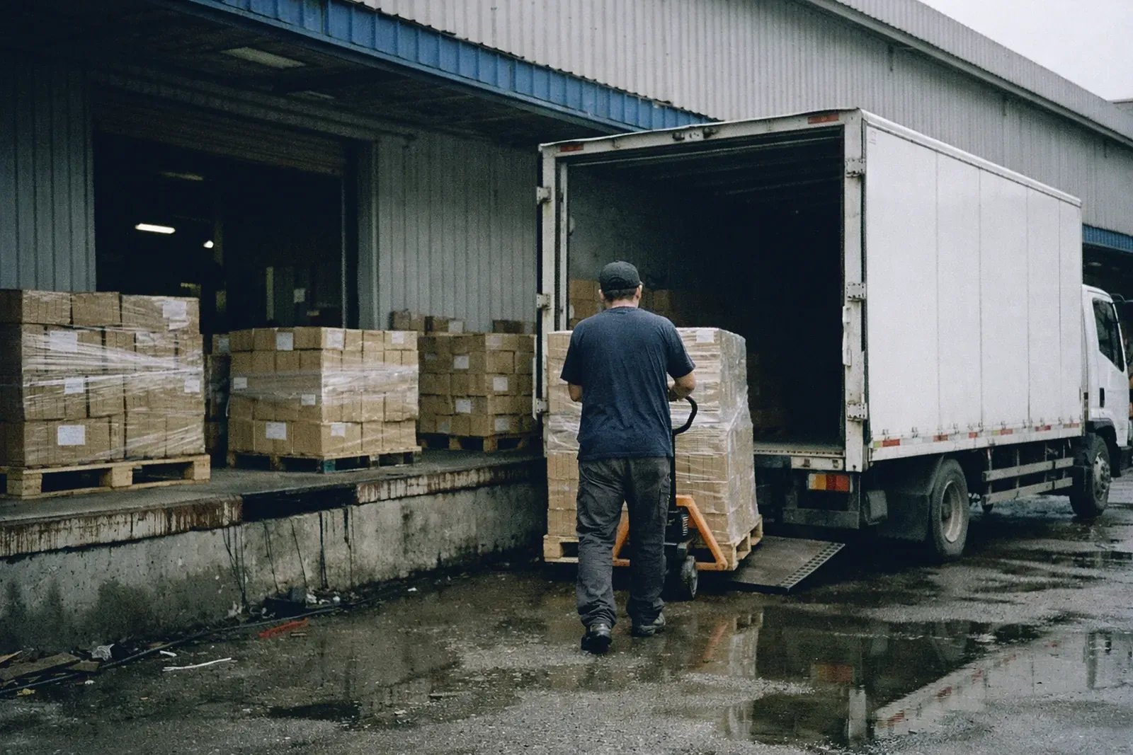 Camion chargé de palettes de cartons filmés au quai d'une usine en Chine, avant le départ vers le port